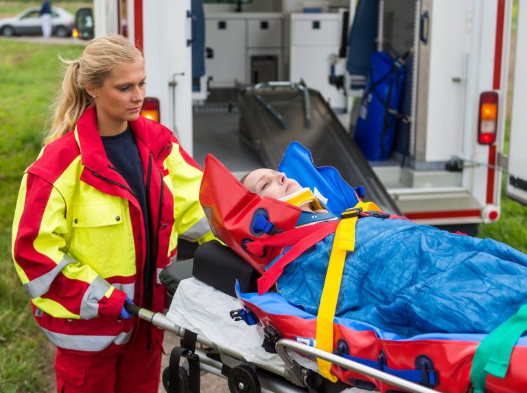 Notfallsanitäterin bringt eine schwer verletzte Patientin in den Rettungswagen